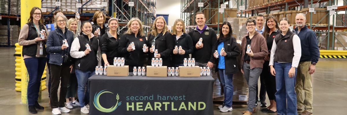 Employees standing in a warehouse holding bottles of milk donated by Kemps