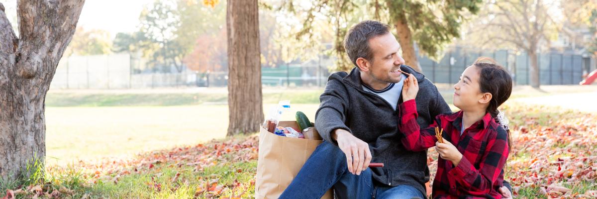 Dad and kid eating pretzels outside on a hill