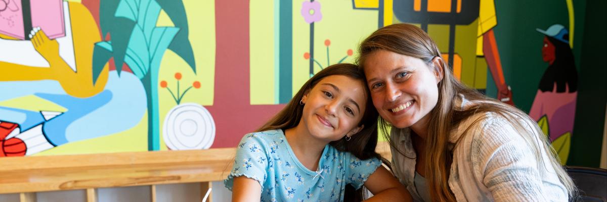 2 people sitting at table one child one adult with bowl of strawberries