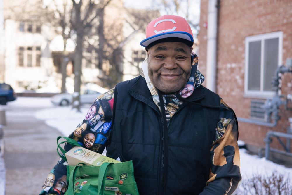 Man smiling and holding a bag full of groceries