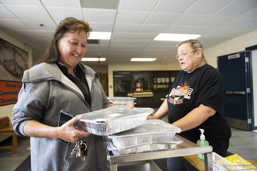 MCK meal pickup A woman holds a prepared meal while smiling