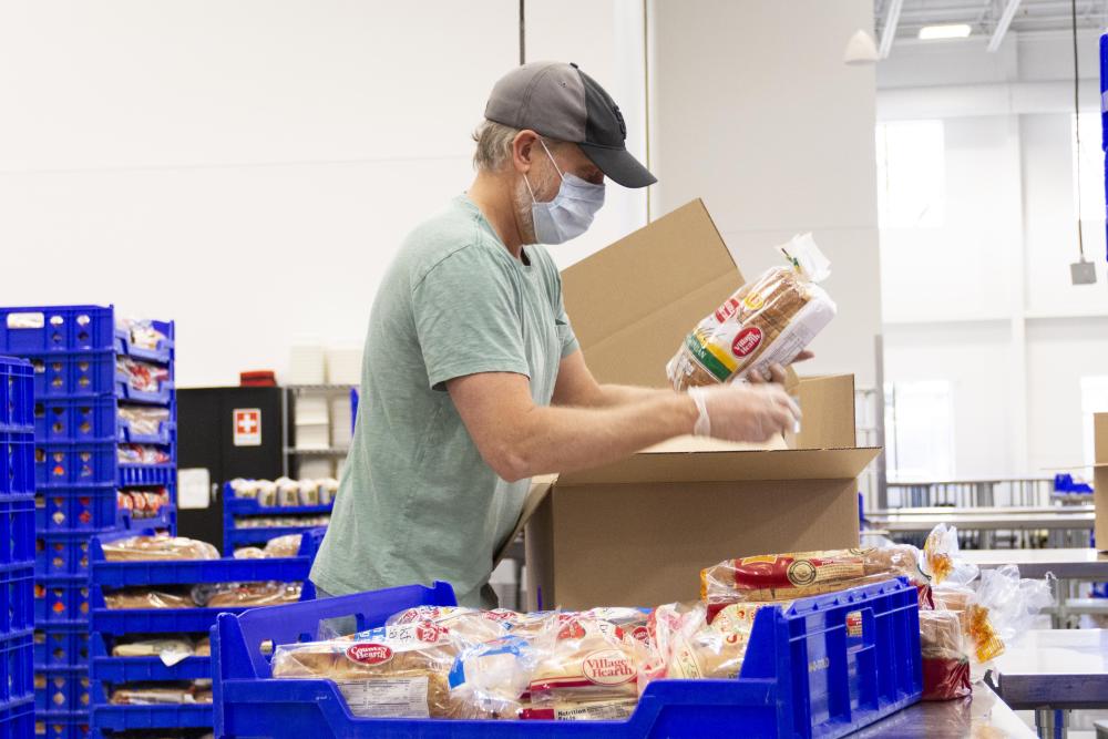 A volunteer puts a loaf of bread into a box