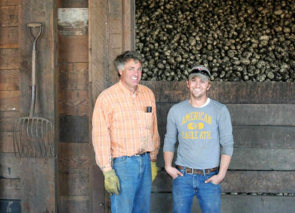 Two farmers stand in front of their harvested crop