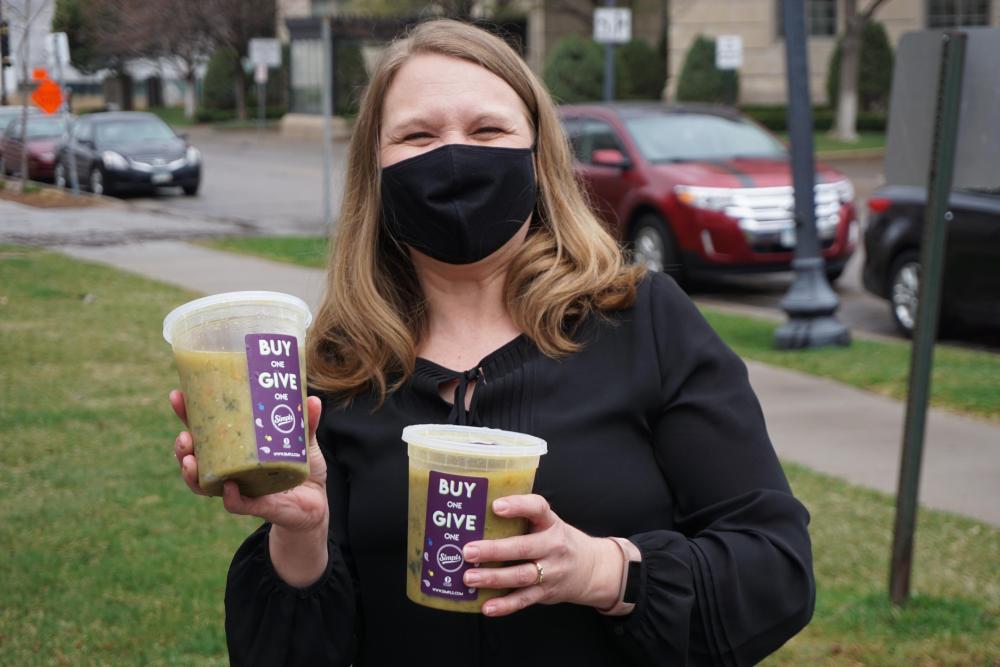 A volunteer holds two containers of soup