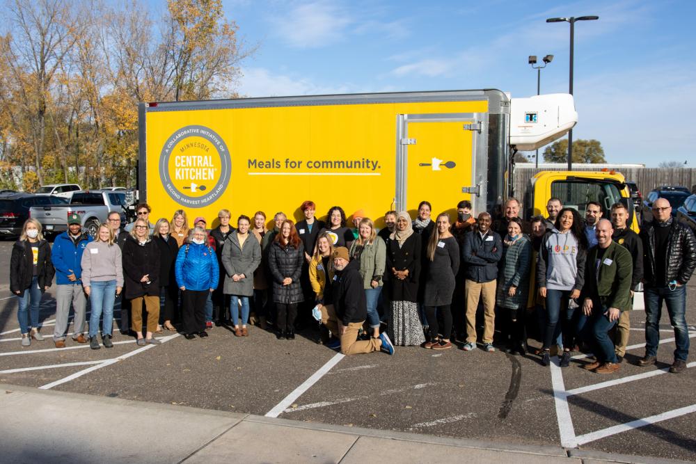A group of people pose in front of a yellow MCK truck