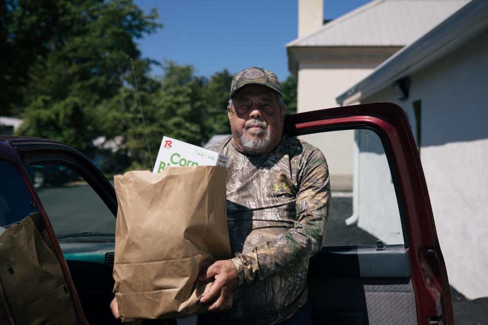Man holding bag of food in front of car door