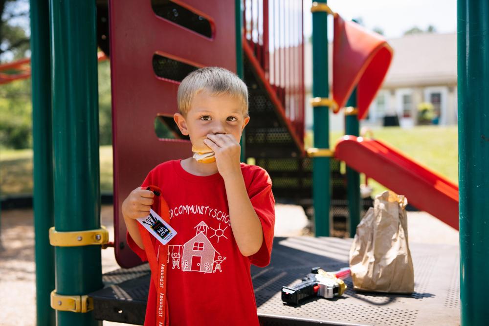 A child eats a sandwich at a park