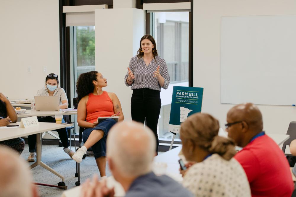 A woman stands in front of a group while speaking