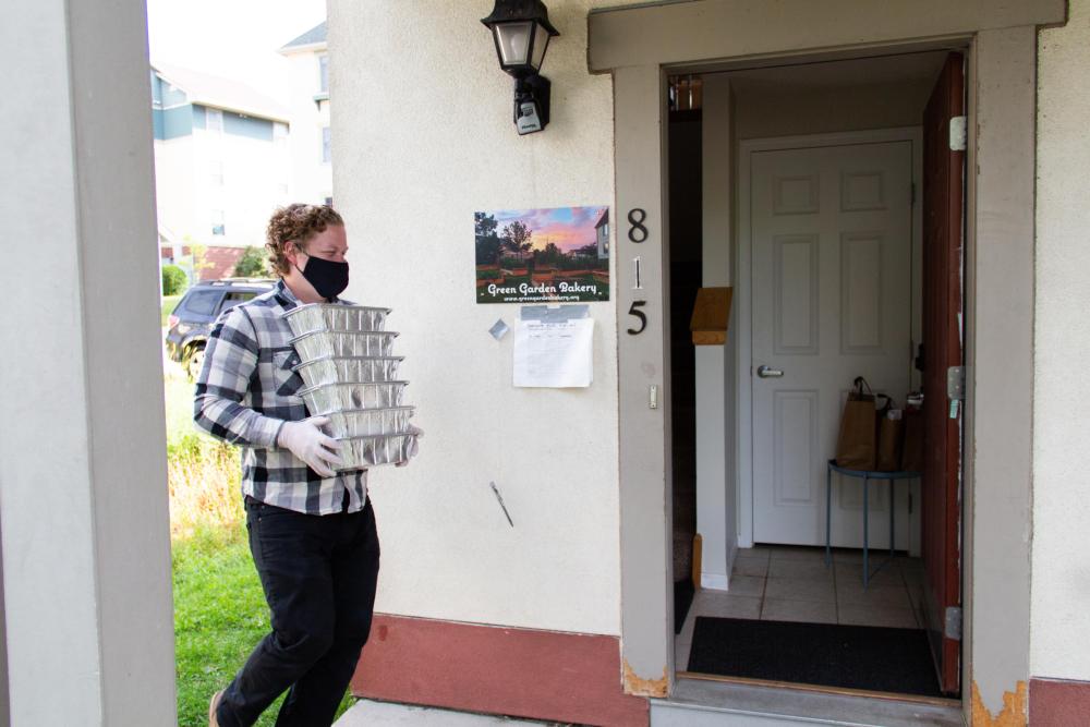 A man carries trays of meals to a neighborhood drop off point