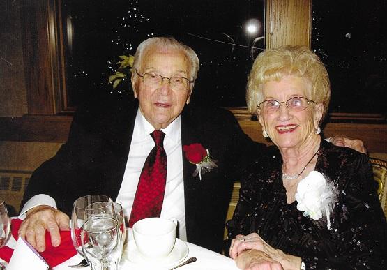 An older couple sits at a restaurant table and smiles