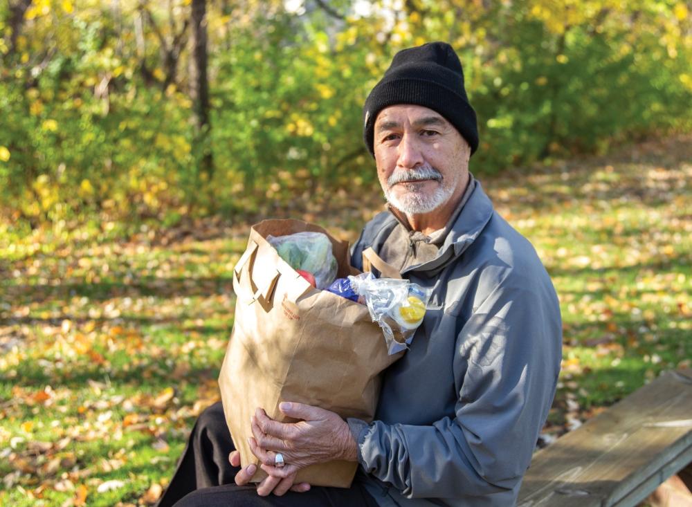 Man with grocery bag outside with hat on