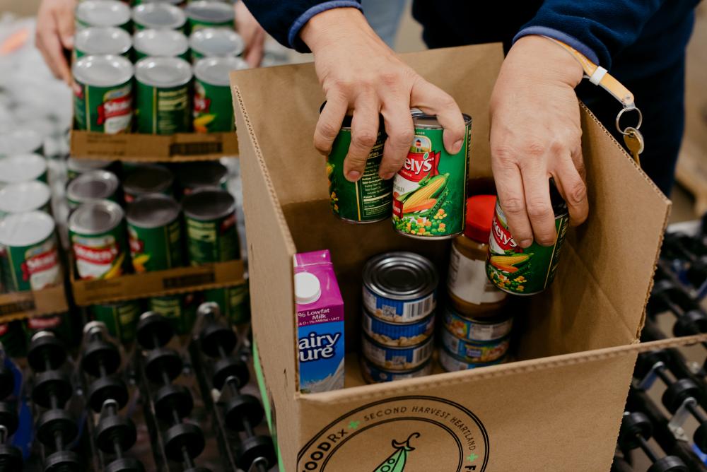 Hands put cans of food into FOODRx box