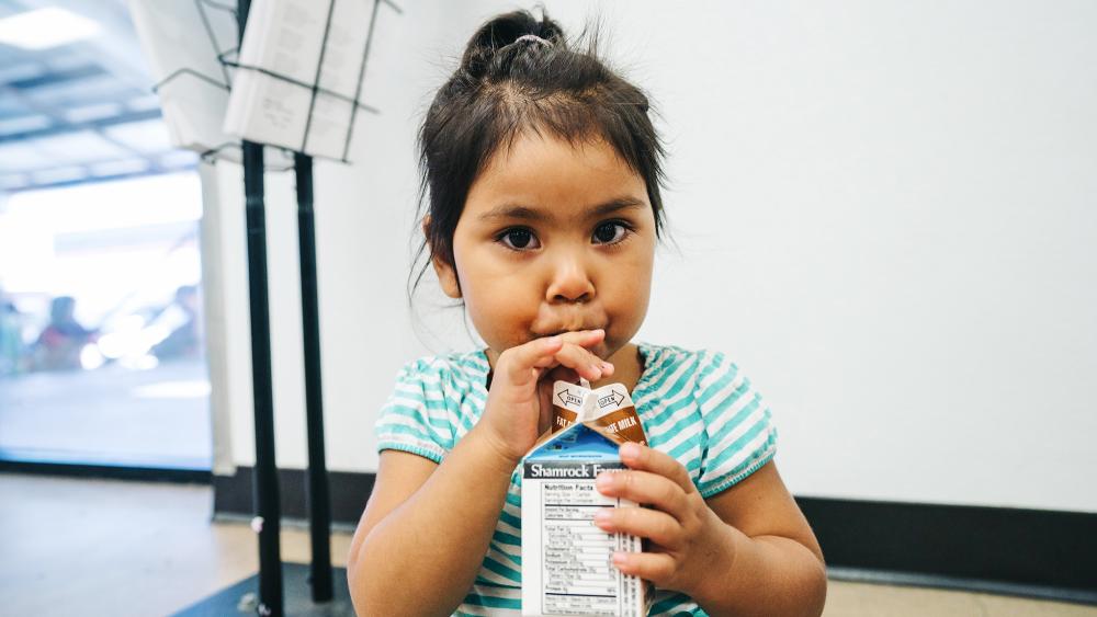 A child drinks chocolate milk from a straw