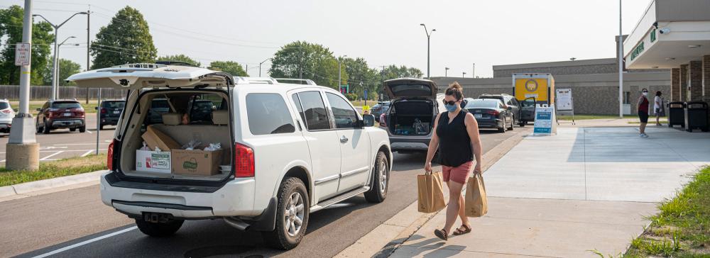 Woman carries grocery bags to her car