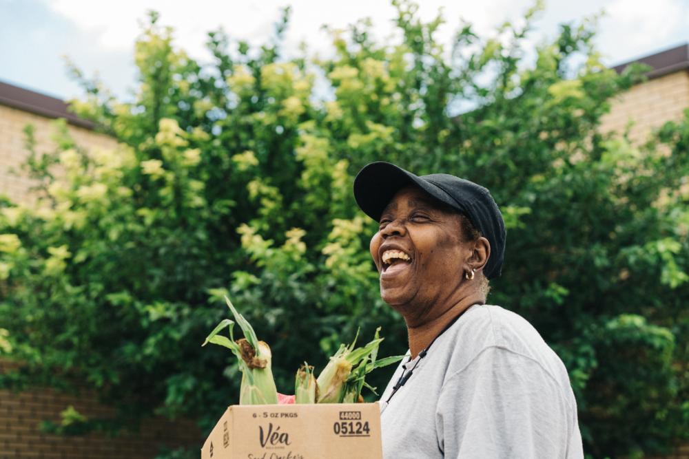 A woman holds a box of produce