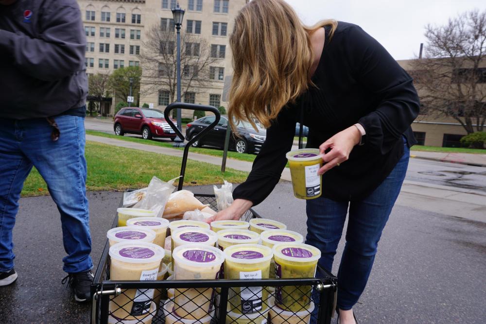 A volunteer loads donated soup into a wagon