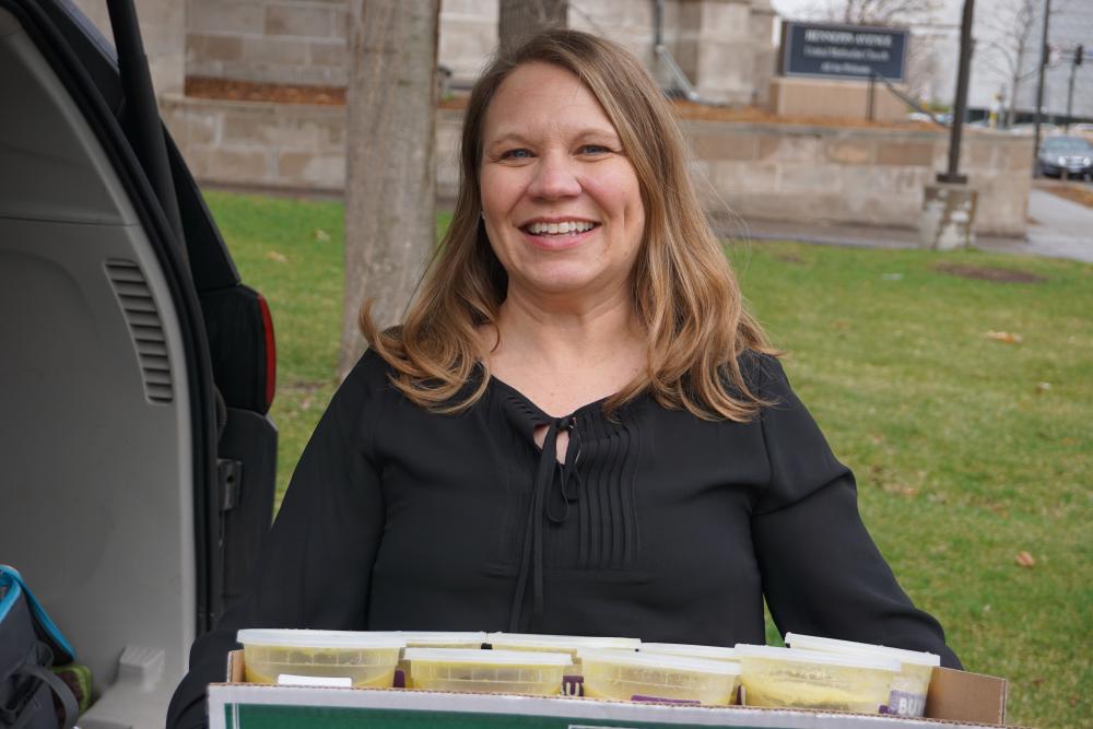 Volunteer outside holding crate of donated soup