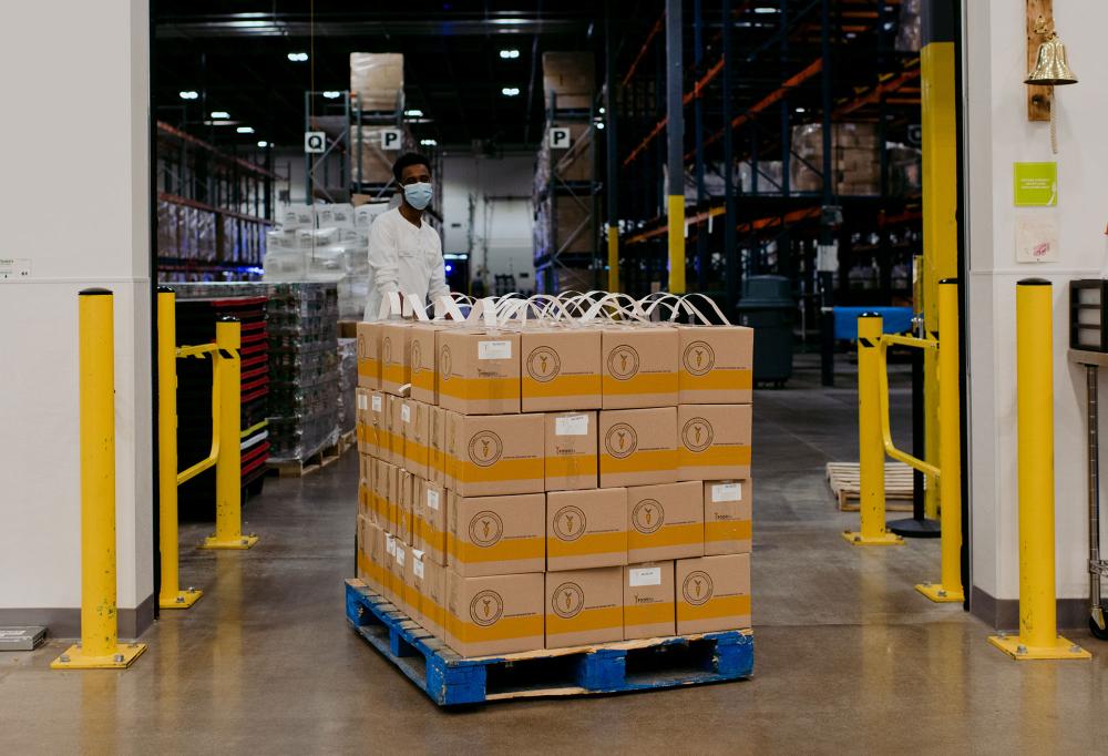 A staff member moves FOODRx boxes into the Volunteer Center with a pallet jack