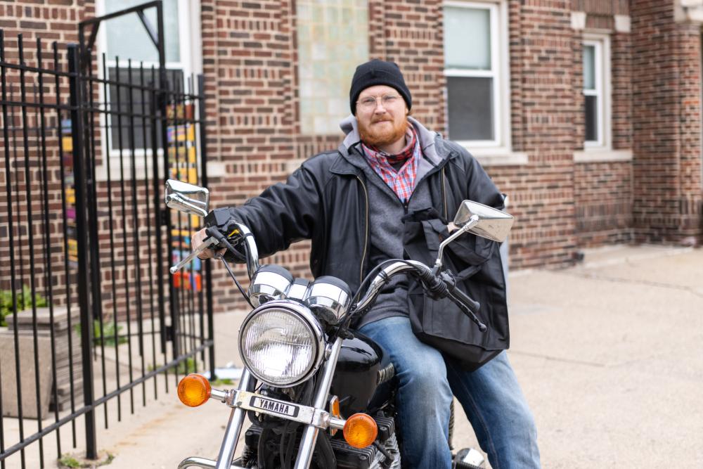 Man on motorcycle receives bag of meals