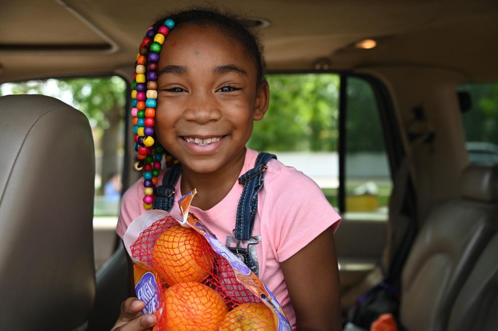 A child holds a bag of oranges and smiles