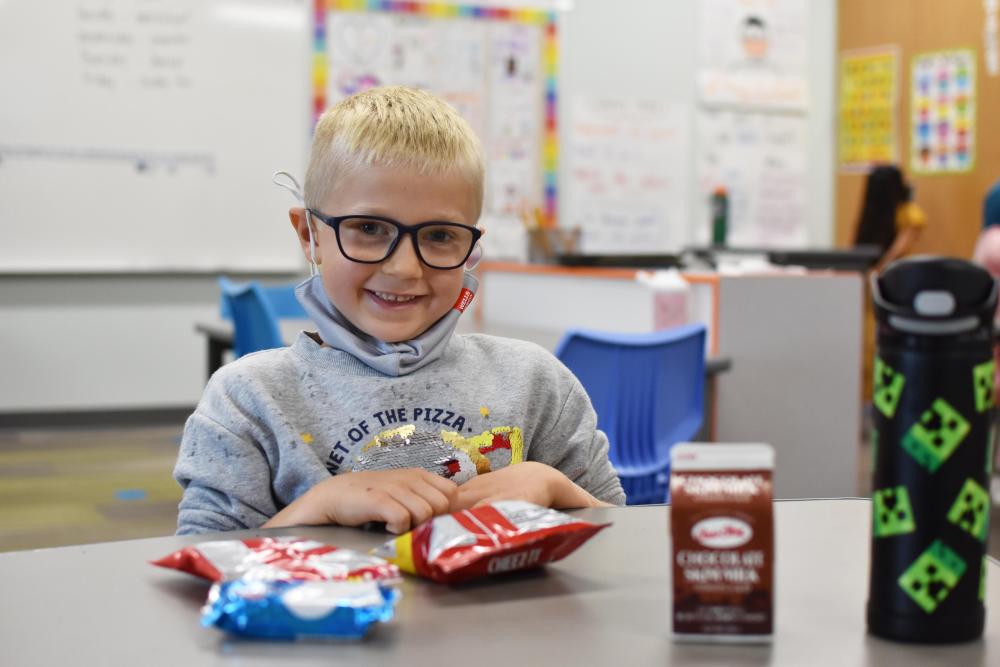 Boy with glasses eats lunch at school