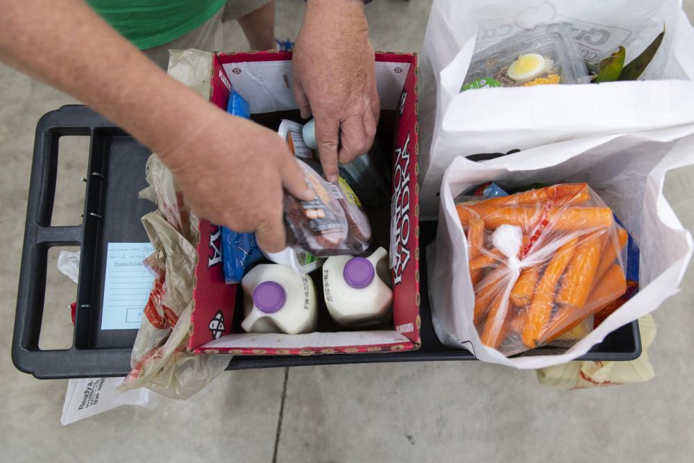 A person puts food into a box on a cart outside