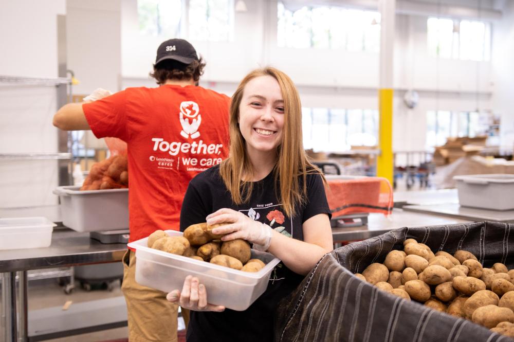 A young volunteer smiles while packing potatoes