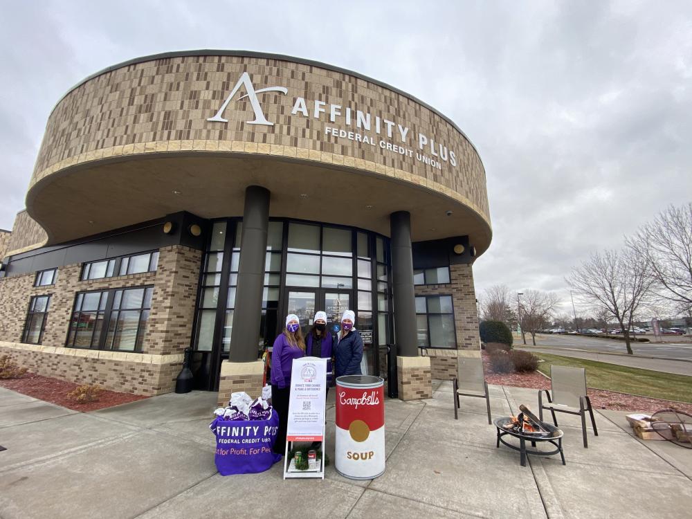 Affinity Plus members in front of branch entrance, collecting coins