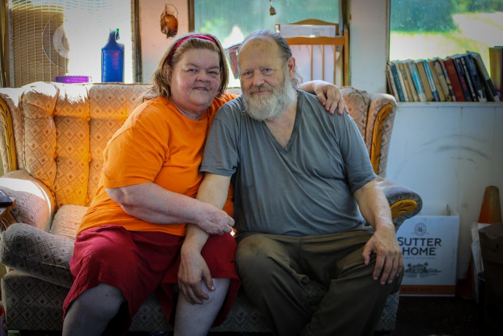 Middle-aged couple sitting with arms around one another