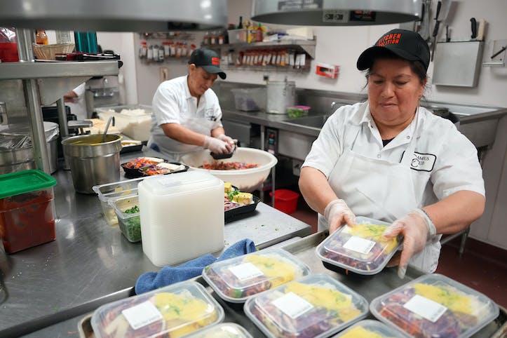 Chefs Hilda Landy, left, and Luz Astudillo, both with Kitchen Coalition, package meals of tofu curry to be delivered to student housing at the University of Minnesota.