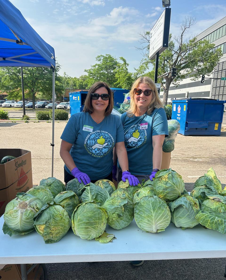 Allison O'Toole and Sarah Moberg handing out lettuce at a food distribution event