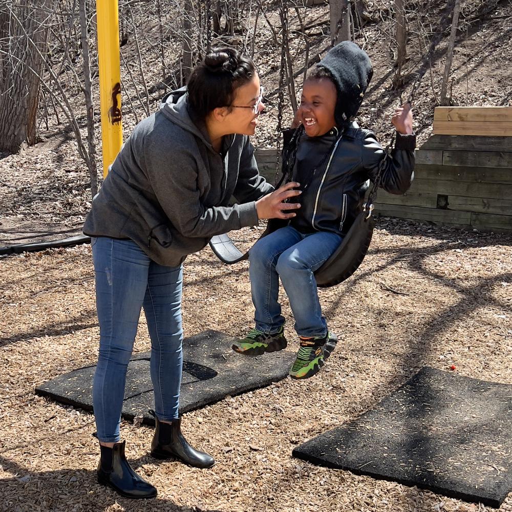 Parent pushes their kid on a swing