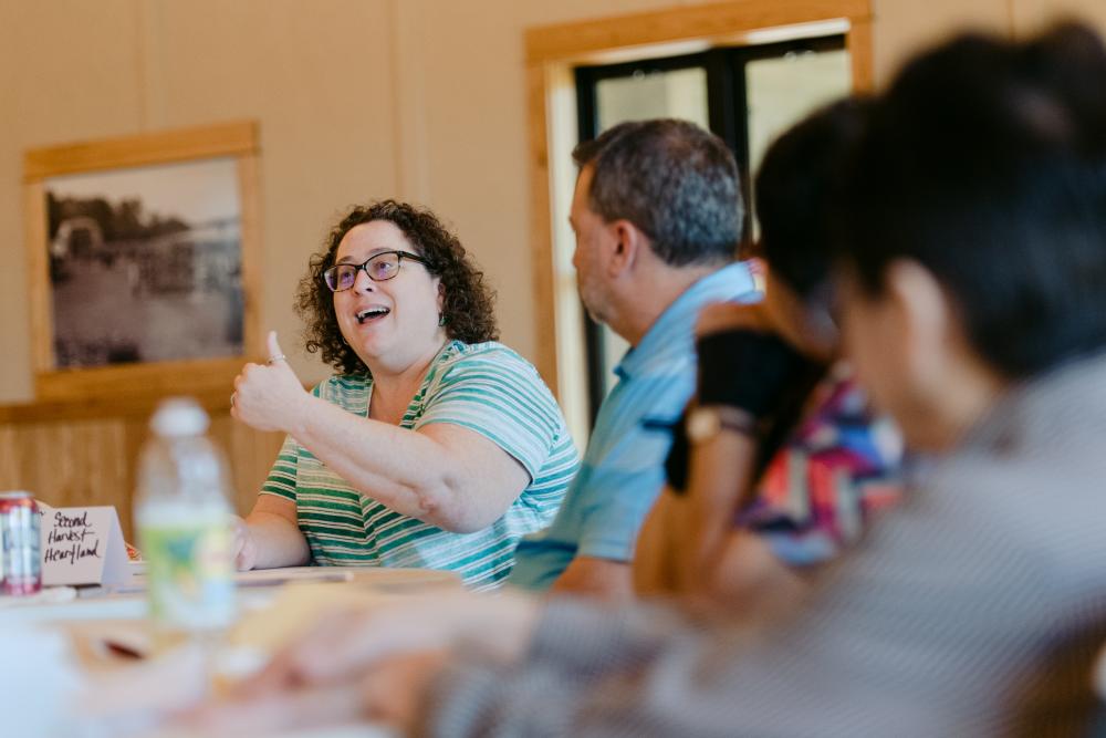 woman speaking to group of people at table
