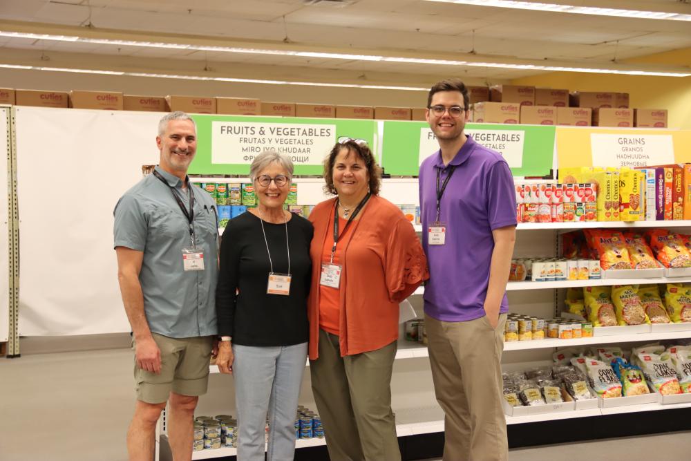Four food bank workers stand inside a grocery store