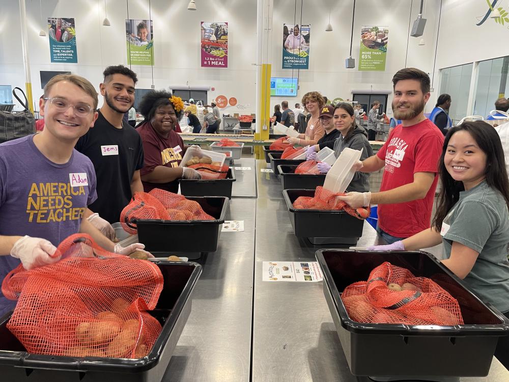 A group of students pack potatoes at a volunteer center