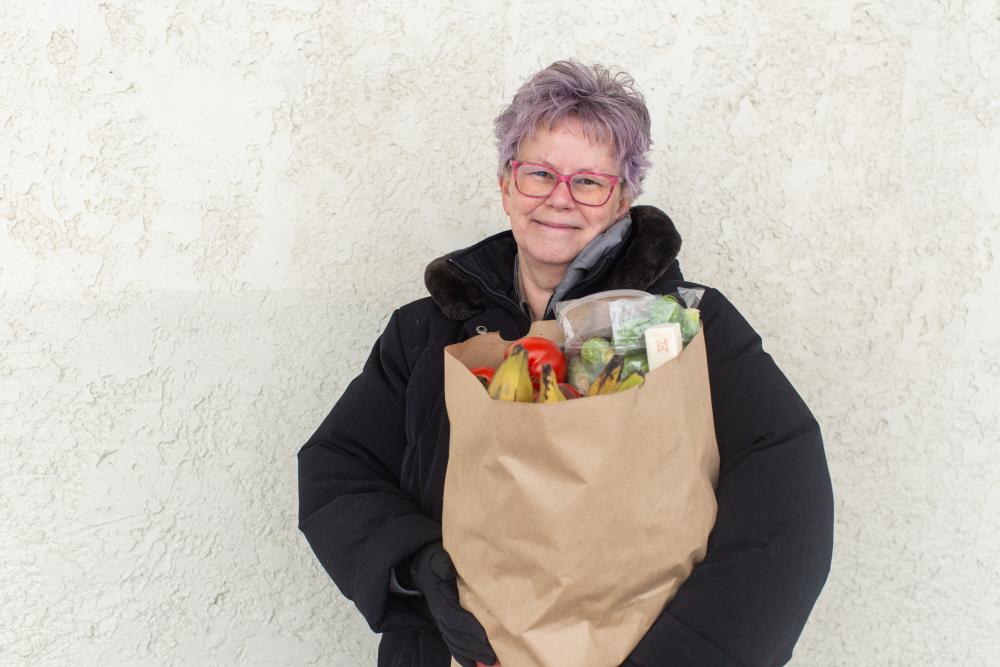 Elderly woman smiling holding a bag of groceries