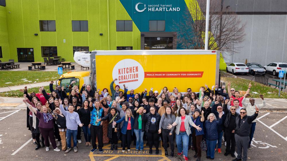 A group of people standing outside a yellow Kitchen Coalition truck at Second Harvest Heartland