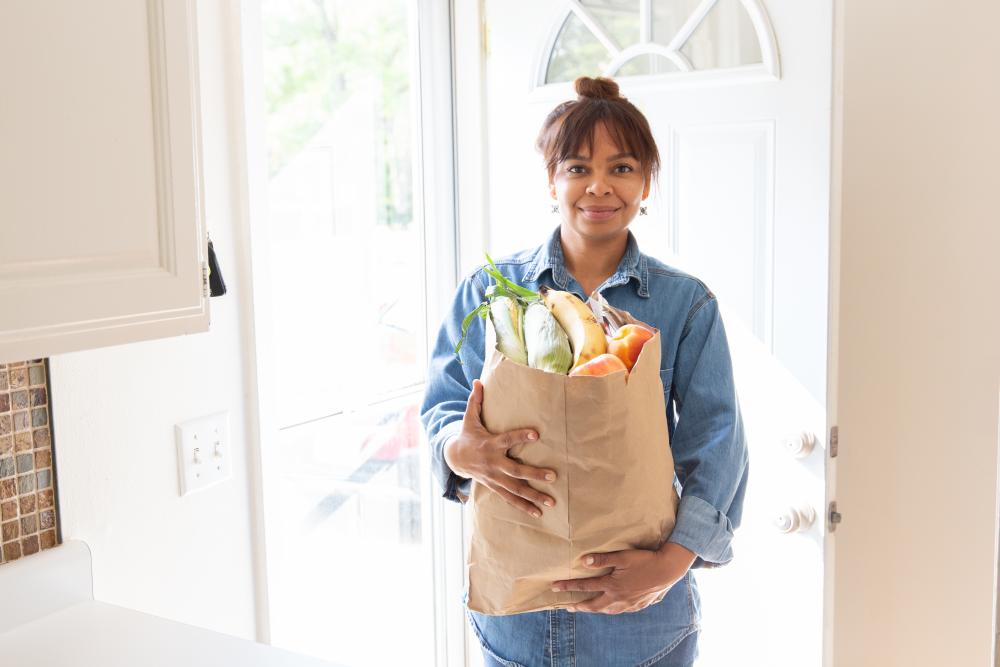 Woman with a bag of groceries in her kitchen