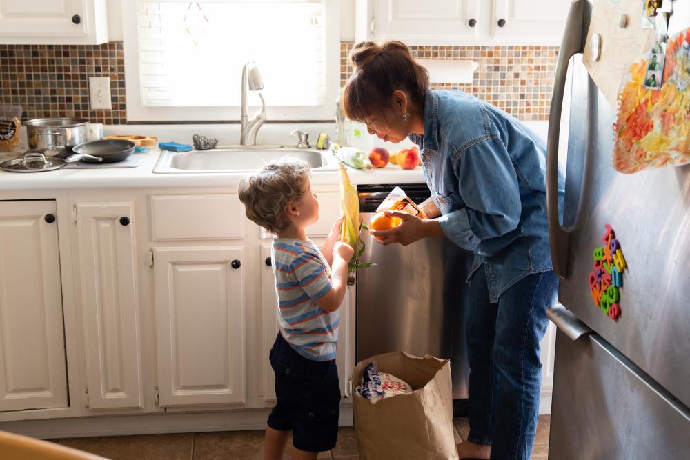 Mother unloading groceries with her son in their kitchen