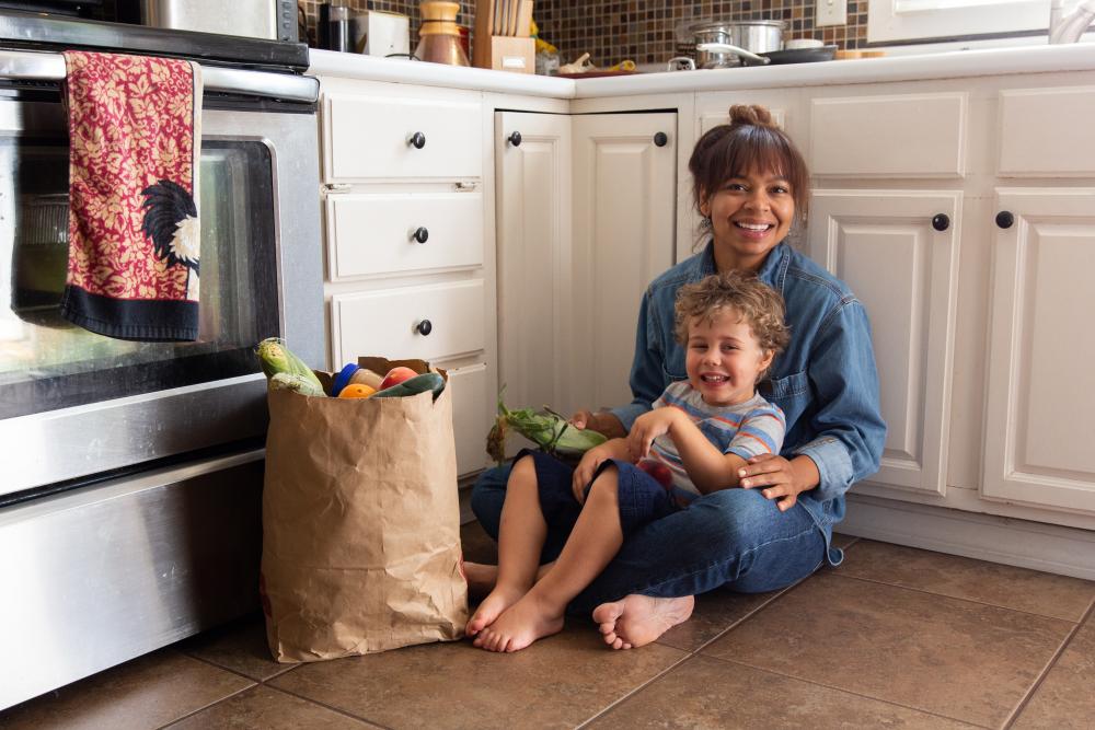 Mother and son sitting in their kitchen with a bag of groceries