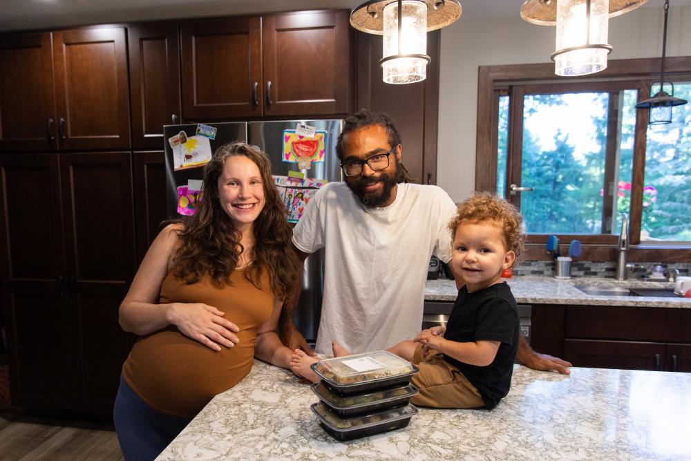 Two parents with their young son gathered in their kitchen