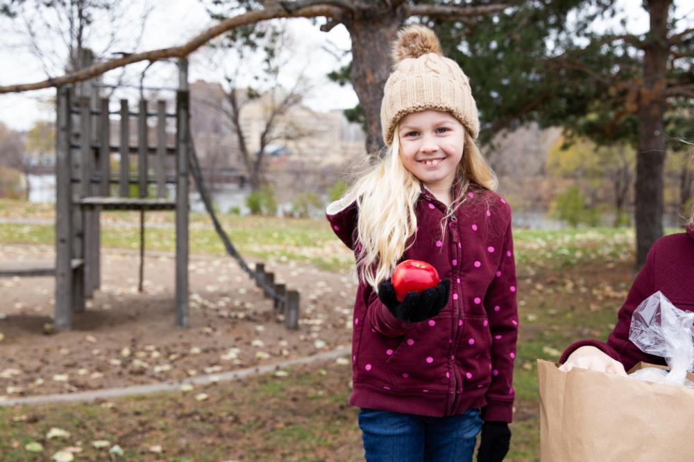 Child holding an apple while at a playground Child holding an apple while at a playground