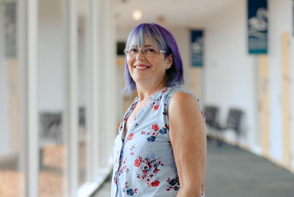 A person standing indoors, smiling