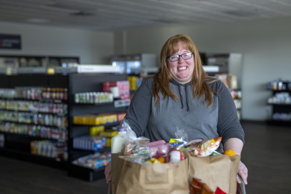 Adult standing inside a food shelf with groceries