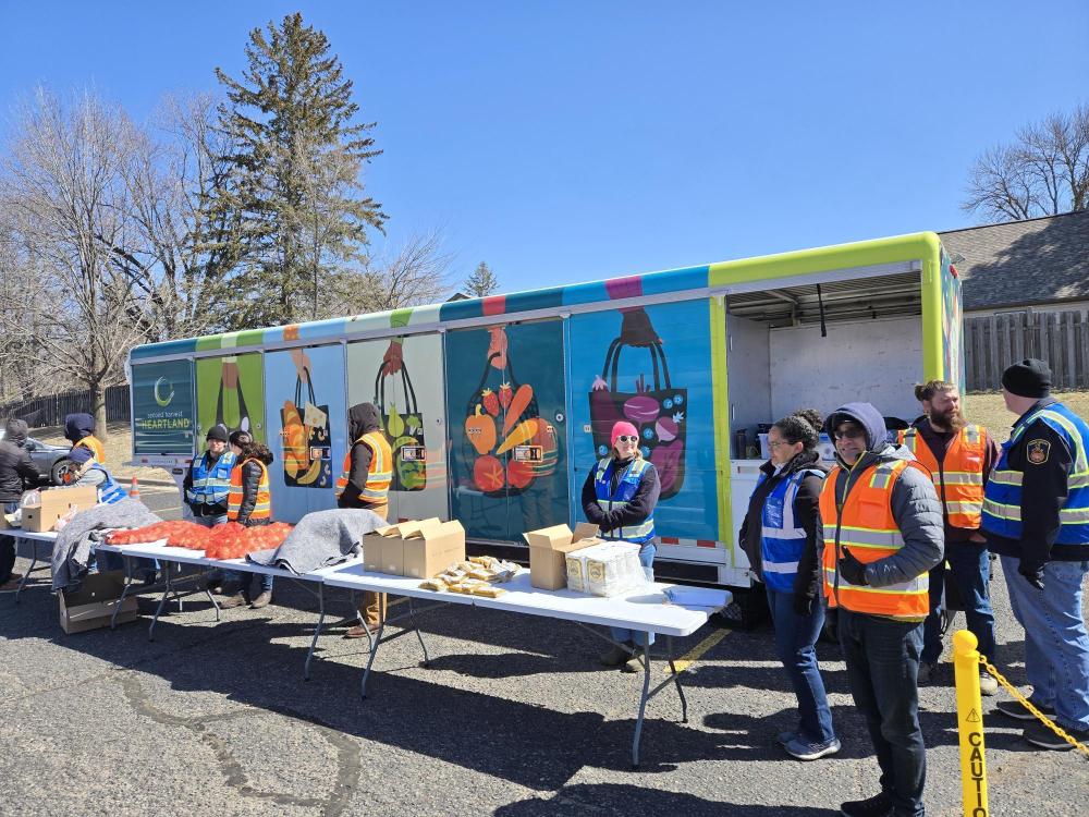 New mobile food distribution trailer A food distribution with volunteers in colorful vests in front of colorful new mobile food distribution trailer