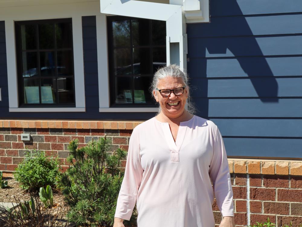 Lisa outside 360 Communities Food Shelf in Rosemount Lisa smiling in a white shirt and glasses outside 360 Communities Food Shelf in Rosemount
