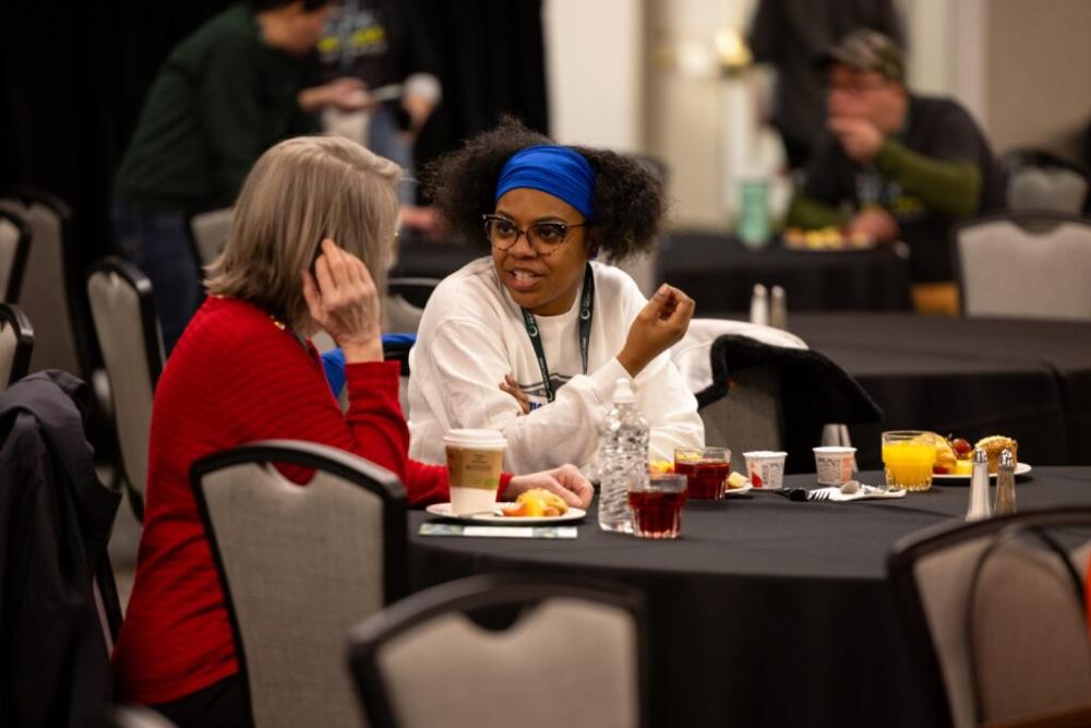 Summit attendees having conversation at a table