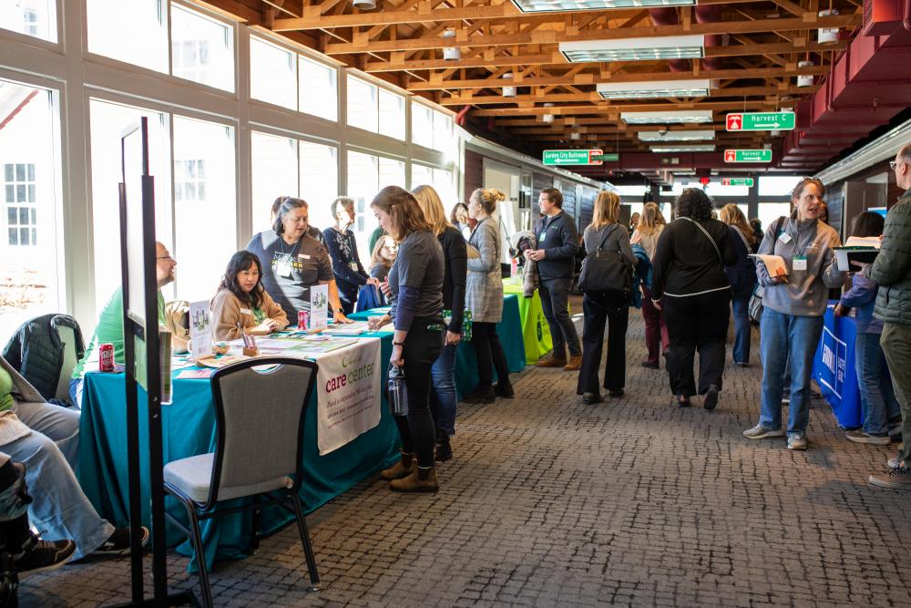 Tables of partners in a hallway with people talking to representatives at each table