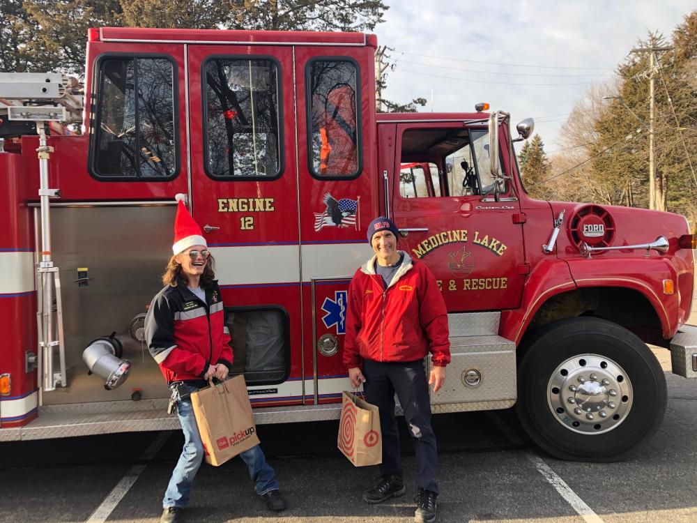 Two people pose with grocery bags outside a Medicine Lake fire truck.