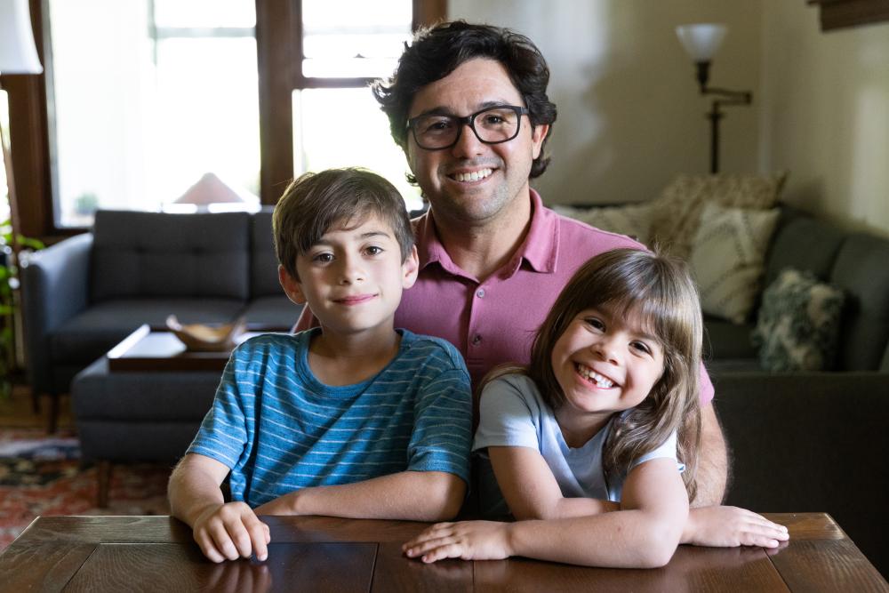3 people seated in room - 2 children and one adult
